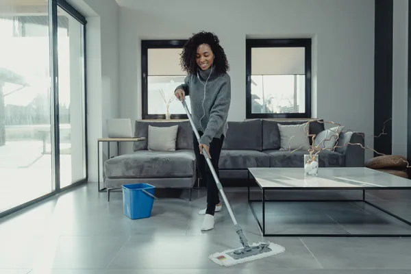 A person mopping a grey-tiled living room